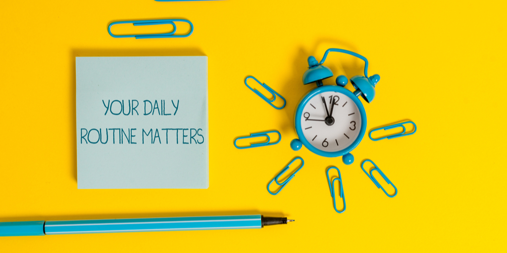 Pen, paper clips, a clock, and a post-it saying "Your daily routine"